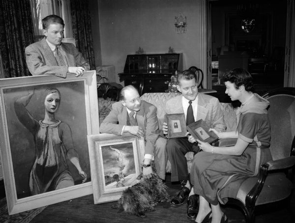 Charlotte Kohler, the governor's wife, examining several works of art which she has chosen to rent for display in the Governor's Residence from the Madison Art Association. Left to right: Robert Grilley, assistant professor of art education at the University of Wisconsin with his encaustic painting done in beeswax entitled "Ariadne"; Aaron Bohrod, artist-in-residence at the university, with his painting "County Fair Acrobats" and Frank Lindl, art teacher at Central High School and the vocational school with two small pins "Withered Tree" and "Native Warriors" that may be worn or framed.