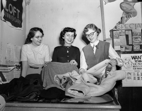 Three members of the Girls' English Club of West High School examine  clothing donated to the annual clothing drive. From left are Nancy Fay, Pam Patterson, and Jean Dahl.