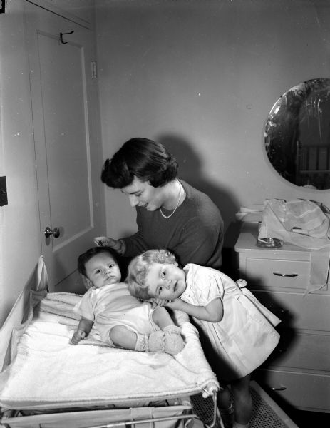 Mrs. Robert C. (Marion) Dennison posing for a portrait with her daughter, Holly, age 2, and her son, Scott, 3 months. She is the wife of Captain Robert C. Dennison who is with the 128th Fighter Wing at Truax Field. The new Air Force families are settled in the Sherman Terrace apartments.