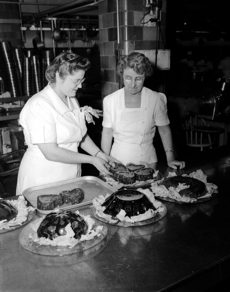 Lillian Steinmann (left) and Gladys Ratcliffe arranging some of the 40 colorful fruit molds at the Smorgasbord held at the University of Wisconsin Memorial Union.
