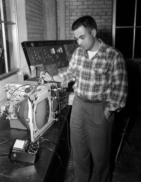 Clarence Marty, a student in the television repair course offered at the Madison Vocational and Adult school, demonstrates how to measure the voltage in a television set accurately and safely.