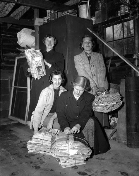 Four members of the Madison West High School girls' club collect newspapers, magazines, books, and cardboard for a paper drive. Proceeds will go toward scholarships for deserving seniors. Pictured from left to right are: Jean Dahl, Day Eye, Gretchen Olson, and Carol Jo Drives.