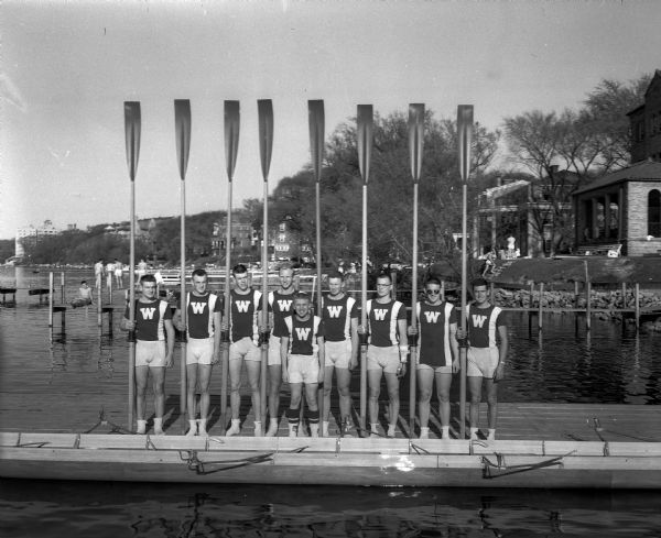 Group image of the University of Wisconsin men's (varsity?) crew team on a pier at the old crew house on Lake Mendota behind the old Red Gym.