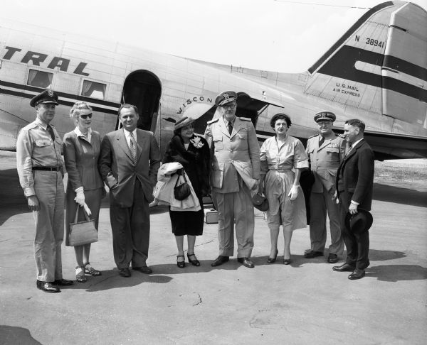 Rear Admiral and Mrs. Roy T. Cowdrey are welcomed by city, state and military officials at the airport. From left: Col. Collins Ferris, commanding officer of the 128th fighter wing at Truax Field; Louise Brown, wife of Justice Timothy Brown; George Forster, Mayor of Madison; Theresa Blue, wife of Captain Robert E. Blue; Captain Robert E. Blue, commandant of the University of Wisconsin naval ROTC unit; and Justice Timothy Brown, State Supreme Court Justice. Rear Admiral Cowdrey was in Madison to review the Armed Forces Day Parade and to give a speech at the annual Armed Forces Day Banquet at the Loraine Hotel.