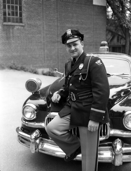 Dane County traffic officer John J. DeSmidt posing in front of a police car.