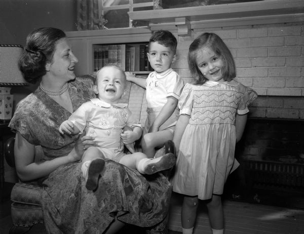 Mrs. Donald Burke of Potomac, Maryland, posing with her children, Dennis, age 1, sitting in her lap, and standing, Patrick, age 3, and Megan, age 4.