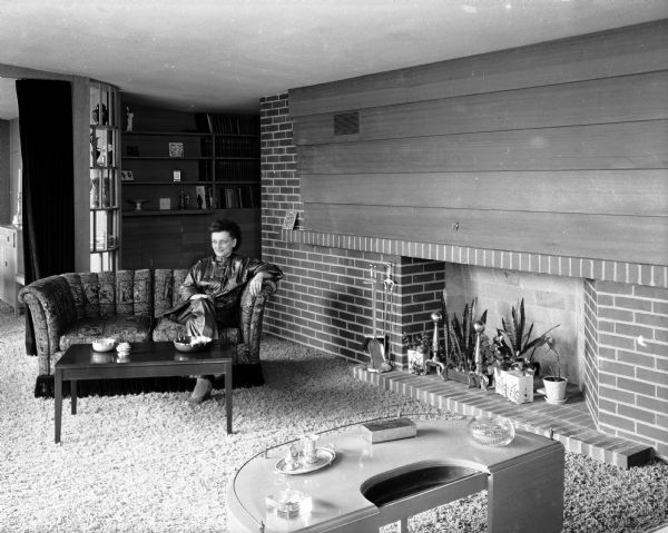 Fern Thompson is sitting in the living room of her new home at 3539 Topping Road, Shorewood Hills. A feature of the room is a redwood and brick fireplace that extends the length of one wall.