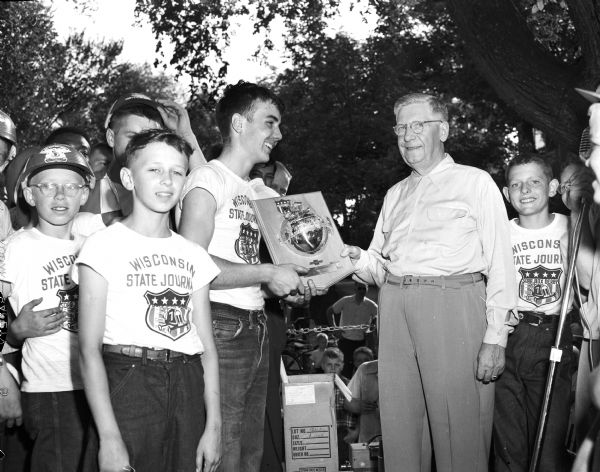 Soap Box Derby winner Roddy Botts receives the Champion Chevrolet trophy from Ralph Hult, right, president of Hult's Capital Garage, during Madison's 12th Annual Soap Box Derby. This was Roddy's fifth try at winning the race. The boy on the left is Dean Elliott, Class B champion. Hult's Capital garage and the the <i>Wisconsin State Journal</i> are co-sponsors of the race.