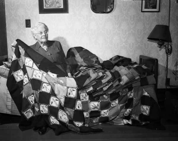 Emma (Mrs. W.J.) Teckemeyer poses with some of the 13 quilted lap robes which she has personally made for the patients at the new Veterans' Administration hospital. Emma has served as a member of the state and national boards of the Service Star Legion, the first women's patriotic organization to be organized after World War I.