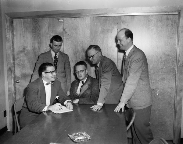 Recently elected officers of the Manufacturers Representatives Association for the 1951-1952 year gather around a table. Seated, left to right, are: George Black, Scott Paper Company; and Harold Seeber, Lipton Tea Company. Standing, left to right, are: A.C. Erickson, Madison Newspapers, Inc.; C.L. DeVries, California Packing Company; and Henry Schultz, Pillsbury Mills, Inc.