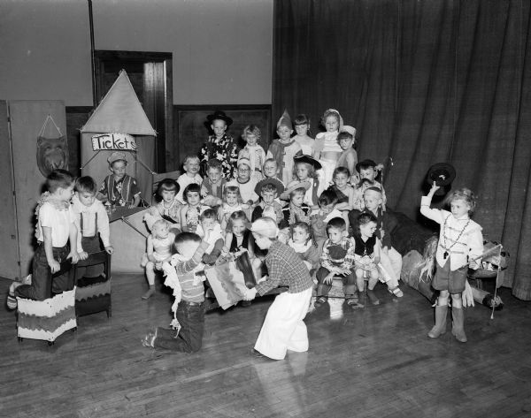 A "lion" is being put through its paces by his "trainer" before a crowd of "circus fans" at Lowell School, as first grade students perform at a dress rehearsal for a circus to be given at the school.