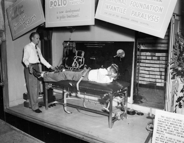 Close-up of a polio resistance exerciser. Dick Murphy, captain of the U.W. boxing team, is shown receiving "treatment" on the machine given by Frank Lam of the Elgin Exerciser Appliance Company, makers of the machine. It will be used in polio treatment at Wisconsin General Hospital and was donated by Sinclair gasoline dealers to the Dane County Chapter of the National Foundation for Infantile Paralysis.