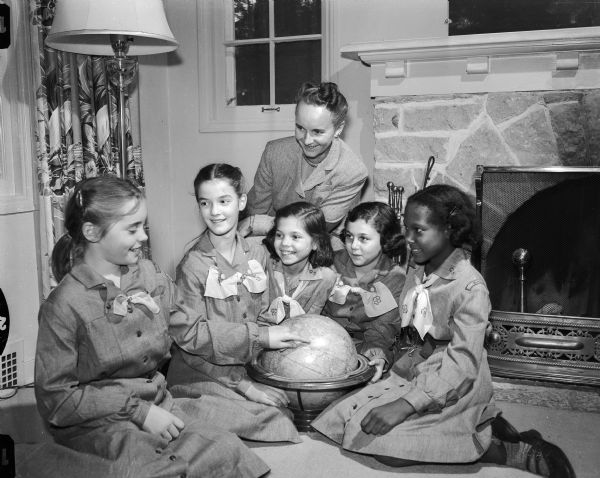 On Girl Scout Sunday, Dane County scouts and their leaders begin the seven service days of Girl Scout week, celebrated nationally to honor Julliette Low, founder of the organization in 1912. Practicing the fourth law of Girl Scouting, "a Girl Scout is a friend to all and a sister to every other Girl Scout," are members of the fifth graders in Troop 95 at Nakoma school  discussing international friendship. Standing is Mrs. Reuben (Margaret) Sand, 4117 Iroquois Drive, co-leader of the troop, and seated left to right, Mrs. Sand's daughter, Sarah; Margot Herriott, 833 Miami Pass; Lois Alt, Ridge Road, Mary Milan, 3812 Cherokee Drive, and Patty Hamilton, Route 3.