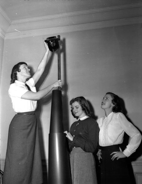 Three members of the YWCA Teen 'N Twenty club put up a lamp post for  the upcoming "Old Lamp Lighter" dance. Left to right:  Leaty Fritz, Helen Salzmann, and Betty Waldman.