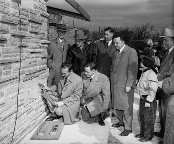 Members of the Westminster Presbyterian church assist in the cornerstone laying ceremony for the new church at 4100 Nakoma Road. Kneeling are James G. Marshall (left), chairman of the building plans committee and the Rev. Richard Pritchard, pastor of the church.  Standing, left to right: James Snaddon, charter member of the church; C.A. Perkins, church member and heating contractor; R.A. Lippitt, trustee and plumbing contractor; and Karl U. Rentschler, president of the board of trustees.