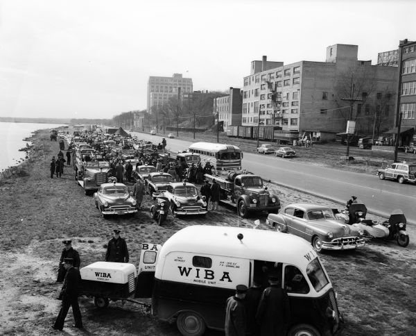 Lineup of parade vehicles at Law Park along Lake Monona for Wisconsin's first civil defense support battalion test in Madison.