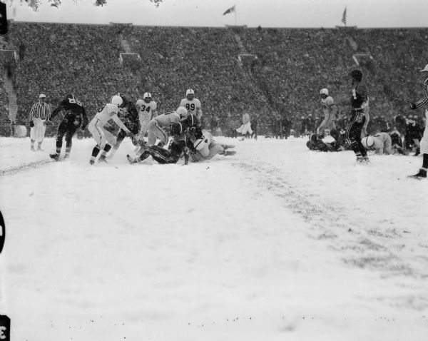 Action shot during the University of Wisconsin-Indiana football game. Rollie Strehlow (#40) drives through the snow for a gain of one yard.
