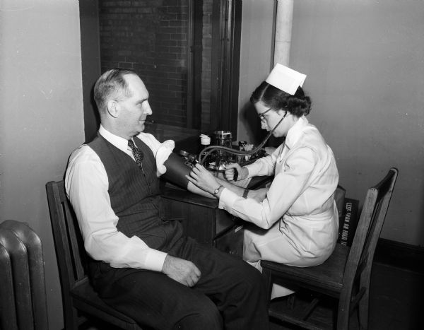 City Attorney Harold E. Hanson has his blood pressure taken by Mary Clancy, Red Cross blood center staff nurse.