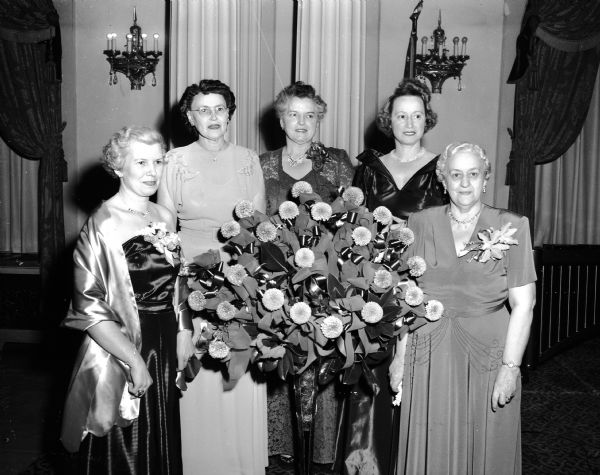 Group portrait of some of the dignitaries who attended the Zor Shrine ladies banquet at the Loraine Hotel. Left to right are: Mrs. Thomas Toal, McFarland, wife of the Zor potentate and honorary chairman; Mrs. Rudolph lindberg, Edgerton, chairman of table decorations; Mrs. Lionel G. Moore, mistress of ceremonies; Mrs. Mack Mitchell, reception and program chairman; and Mrs. Fred Mason, Zor auxiliary chairman and banquet chairman.