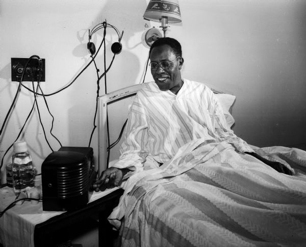 Zellie Jackson of 522 East Wilson Street, a tuberculosis patient at Lake View Sanatorium, listens to a radio while lying in bed.
