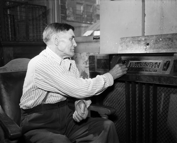 Jack Wick listening to a radio at his home after recovering from tuberculosis.