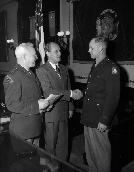 Governor Walter Kohler, center, congratulates Colonel Carl A. Flom on the activation of the 5956th Organized Reserve Corps School. At left is Major General Ralph Olson. The school will enable Madison area reserve corps officers to receive the latest training equivalent to the academic level of college training.