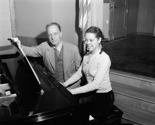 Joan Taliaferro sitting at a piano with Madison Civic Symphony orchestra conductor Walter Heermann. She is to play with the orchestra at their young people's concert.