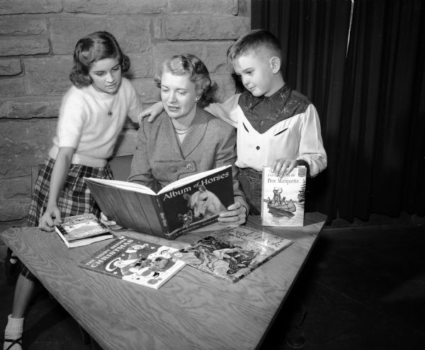 A woman reads to two children at the First Unitarian Church on University Bay Drive prior to the upcoming Theta Sigma Phi Alumnae "Holiday Book Fair" that benefits the professional women in journalism fraternity's writing aides project.