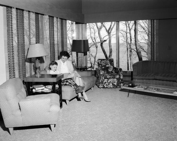 Philip and Kathleen Rosenthal's salmon-red house in Shorewood Hills, designed by Milwaukee architect Alvin Jansama and built in the late 1940's, is on two levels, reversing the modern trend of building on one level. Kathleen Rosenthal and her daughter Leslie, age 5, are seated on the red and white sectional sofa.