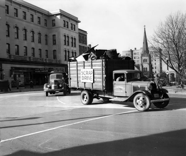 Scrap metal trucks travel along South Carroll Street during the Cambridge Scrap Metal Parade on the Capitol Square. The Park Hotel is in the background. Proceeds from sale of the metal went towards a movie projector for Cambridge High School.