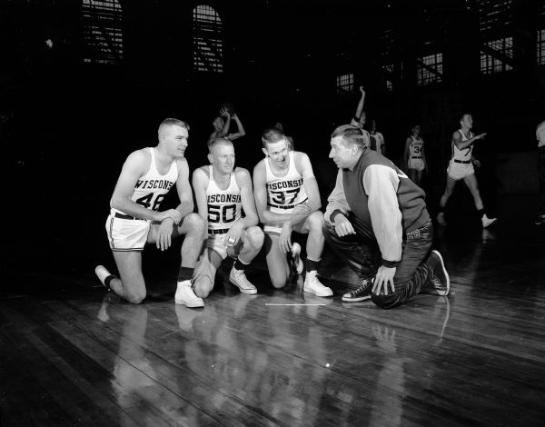 Coach Harold "Bud" Foster, right, is shown at the start of his 18th season, kneeling with three of his forwards. They are Harvey Kuenn (#48), Carl Herreid (#50), and Pete Anderson (#37).