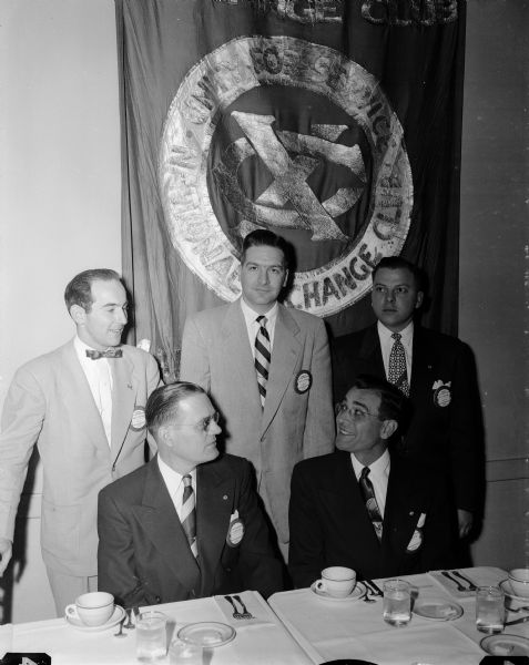 Seated at the banquet table are D. Russell Bontager, Indiana legislator, at left, and Henry Marshall, Galesburg, Illinois, at right, who were guests of the Madison Exchange Club's meeting. Mr. Beontager was the featured speaker and Mr. Marshall is the new regional vice-president of the Exchange Club. Madison Exchange Club members standing left to right: Felix Kremer, bulletin editor; Harley Thronson, president; and Dr. Donald Bergenske, program chairman.