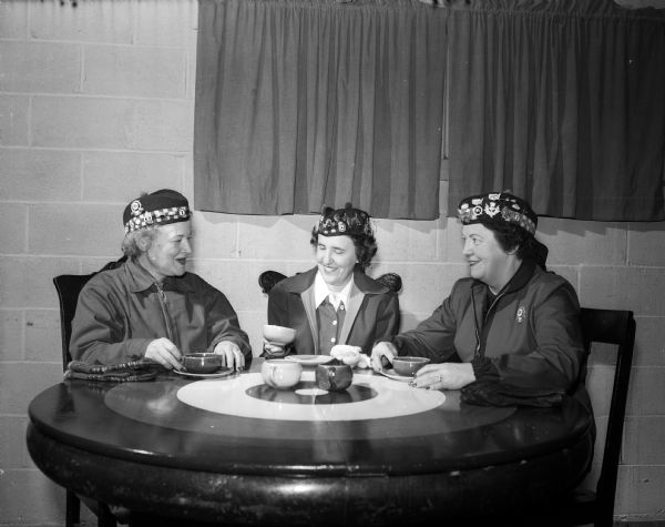 Group portrait of three players for the Madison Toories, a women's curling group, sitting at a table. Left to right: Freida Waddell, Helen Carlson, and Myrtle Jamieson