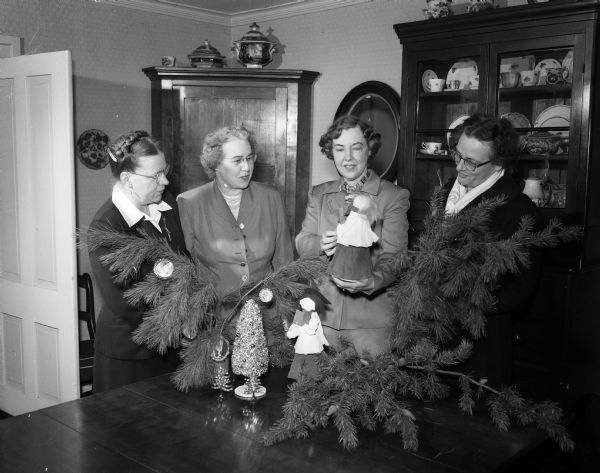 Four members of the West Side Garden Club examining Christmas holiday table decorations at their Holiday House Tea.  Left to right are Mrs. Wilfred J. Harris, Florence Stephens, Ruth Poehmann and Mary Rehfeld.