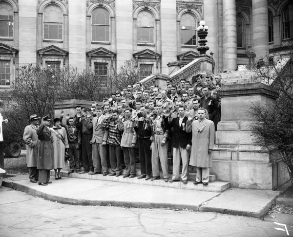 Mayor George Forster, far left, looks on as Col. Robert D. Montagne of General Mitchell Field, Milwaukee, also at left, administers the oath of enlistment to the forty-seven "Operation Badger" air force recruits. Also witnessing the ceremony (at left with Montagne and Forster) is Miss Geri Robinson, Miss Recruiter for Wisconsin.