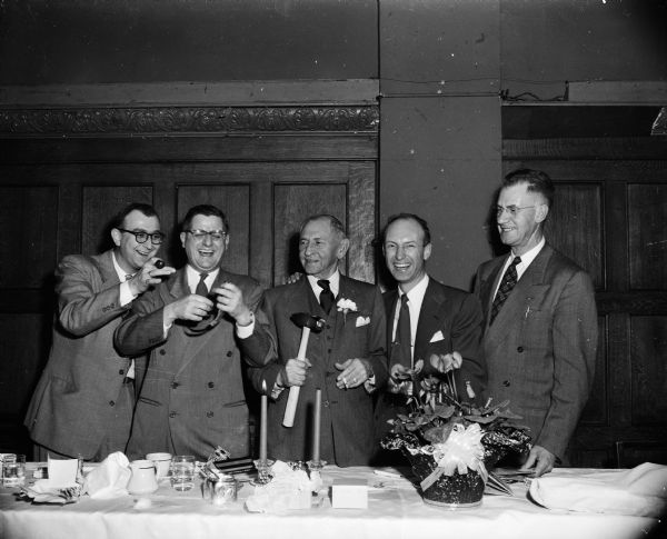 Group portrait of five men at the speakers table for a company dinner for employees of the Wolf, Kubly, and Hirsig Company at the Park Hotel. Left to right are: Ed Linde; Stanley V. Kubly, company president; Louis Hirsig, who was celebrating his 75th birthday; Cy Klingele; and Forrest Her.
