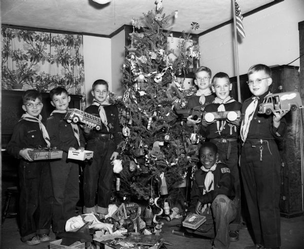 Members of Cub Scout Pack #304, sponsored by St. Mark's Lutheran Church, place toys under their Christmas tree that will be donated to the Empty Stocking Club. Kneeling in front is Levy Hardin, Den #7. Standing left to right: Bobby Hann, Den #1; Jerry Ulrich, Den #5; Billy Hoppe, Den #4; Mark Hotlen, Den #2; Robert Irvine, Den #3; and Ronald Hughes, Den #6.