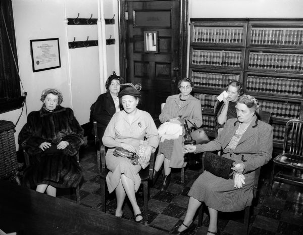 Six irate women drivers sit in the office of superior court judge Roy H. Proctor's office to protest his dismissal of a traffic charge against a male driver who disbelieved a woman's turn signal. The women are, left to right: Mrs. E.B.A. Sokoloski, whose turn signal was ignored; Mrs. Benson H. Paul, president of the Madison Woman's Club; Mrs. Dorothy Wagner and Mrs. Hattie Kinzie, committee chairmen of the Business and Professional Women's Club; Mrs. Betty Cass Willoughby; and Mrs. Esther Hemingway, president of the business women's group.