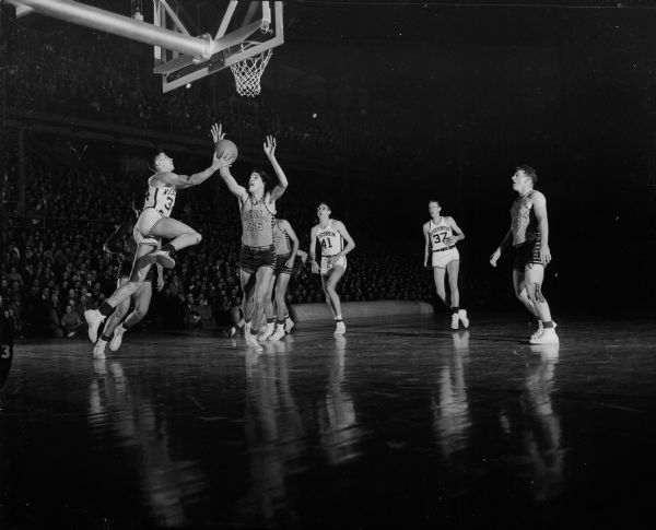Charles Siefert (#34), at left, and Albert "Ab" Nichols (#8), right, are shown going up for shots that helped the University of Wisconsin's basketball team defeat Loyola University's team 66-47.