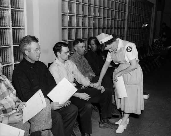 Dane County Highway Department employees line up to donate blood during the annual Red Cross blood bank drive. Left to right: James O'Connell, Russell Roeder, Robert Wendt, and Red Cross employee Mrs. H.E. (Jennie) Helm.