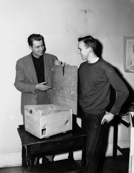 At left, Lynn Hazelbaker is shown demonstrating the winning entry of the Madison Youth Council's rat bait box building contest built by Edward Ripp, age 14. At right is Paul Lucas, youth council chairman of the contest.