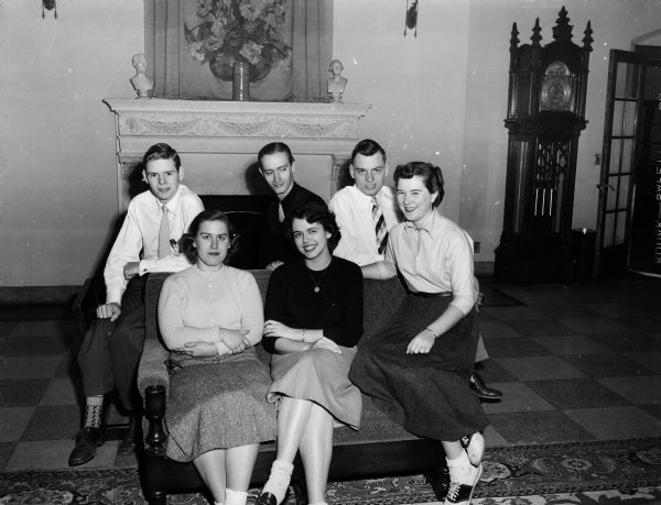 Group portrait of the honor court for the Rai-Molay Christmas dance. The court is made up of members of Order of Rainbow and the Order of DeMolay. The girls, left to right in front, are: Carole Jo Drives, Queen Nancy Fay, and Suann Burns. The boys, left to right, are: Richard Massey, Dennis Crabtree, and Donald Benrud.