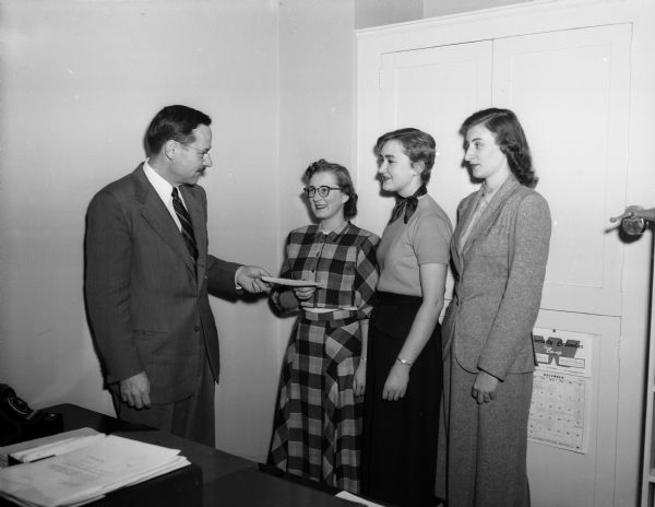 Paul I. Trump, left, is shown presenting a Madison Zonta Club scholarship award to Louise Yanke of Milwaukee, right, while the two other recipients of the awards, Margaret Hoekstra of Marshfield and Marianne Uetzmann of Waukesha, also at right, look on. Mr. Trump is director of admissions and chair of the scholarship committee at the University of Wisconsin.