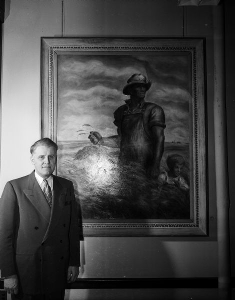 Dean R.K. Froker of the University of Wisconsin College of Agriculture stands beside the late John Stuart Curry's painting "The Good Earth". The painting hangs in the office of the dean and was painted while Curry was artist in residence at the college.
