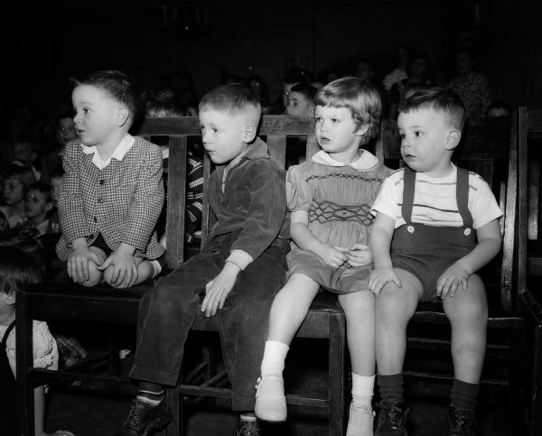 Four children watch a puppet show at the annual Christmas party for children and grandchildren of University Club members.
