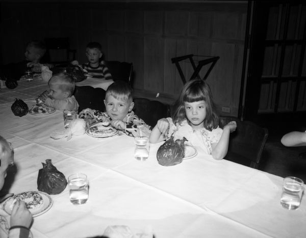 Five children eat snacks at the annual Christmas party for children and grandchildren of University Club members. In the foreground are, left to right: James Penn, Gilbert Peterson and Pamela Crane.