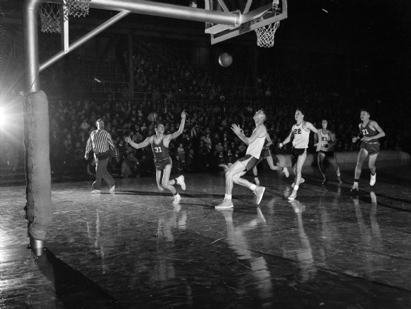 Chuck Brendler (center), Ted Blackney (#22) and Jim Kurth (#21) of Madison East, and Don Hawkins (#31) of LaCrosse Central, wait for a rebound as East defeated LaCrosse Central 57-44 in the second game of the annual holiday doubleheader at the University of Wisconsin-Madison Field House.