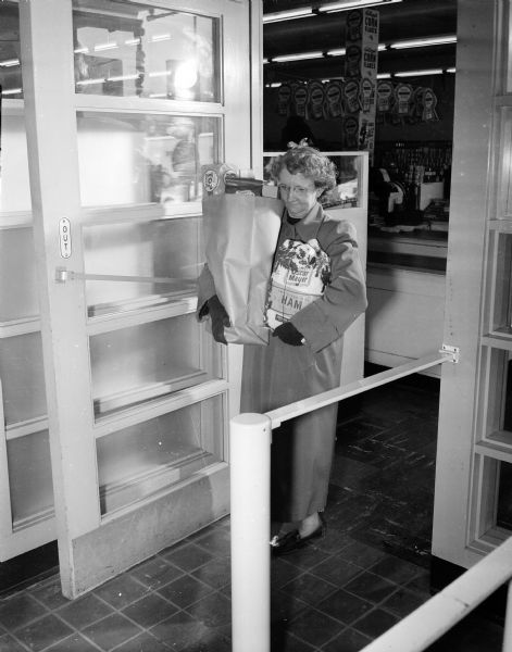 A woman carries groceries out of the National Food Store in the Shorewood Shopping Center, located at 3244 University Avenue in Shorewood Hills. The Magic Eye Doors opens the door for the shopper automatically.