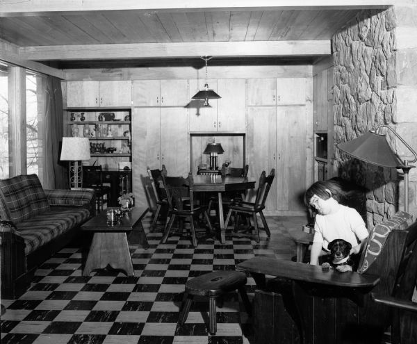 One of the daughters of the Doctor Booher family sitting with one of the pet dogs in the lower level family room of their new home overlooking the Baraboo river near Reedsburg.