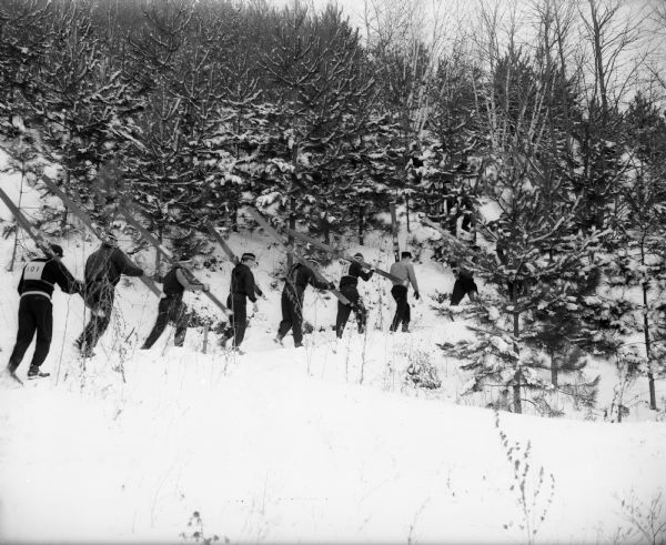 A number of competitors in the annual meet of the Blackhawk Ski Club head up the steep hill for another jump off the ski slide at Tomahawk Ridge near Middleton. No. 101 is Ken Wahl of the Wisconsin Hoofers Club, and the skier in the center with a checkered cap is Mike Johnson of the Wisconsin Rapids TriNorse Club.